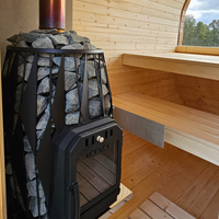 Wood-fired stove in a wooden sauna with benches and a view of trees outside.