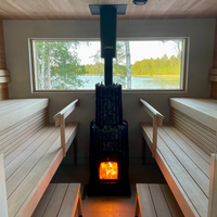 Sauna interior with wooden benches and a lit stove, featuring a window view of a lake and trees.