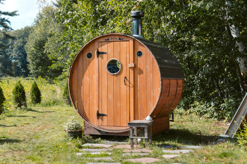 Cedar barrel sauna in a green Australian garden at dusk
