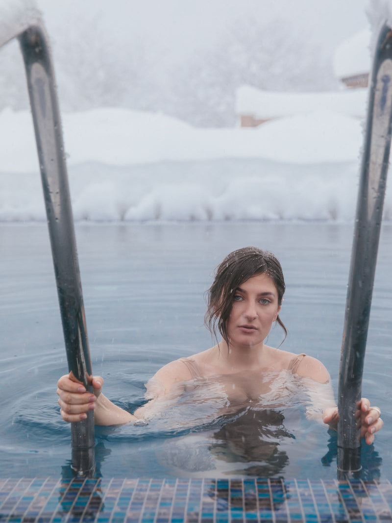 Person doing cold water immersion outdoors in winter, representing cold exposure.
