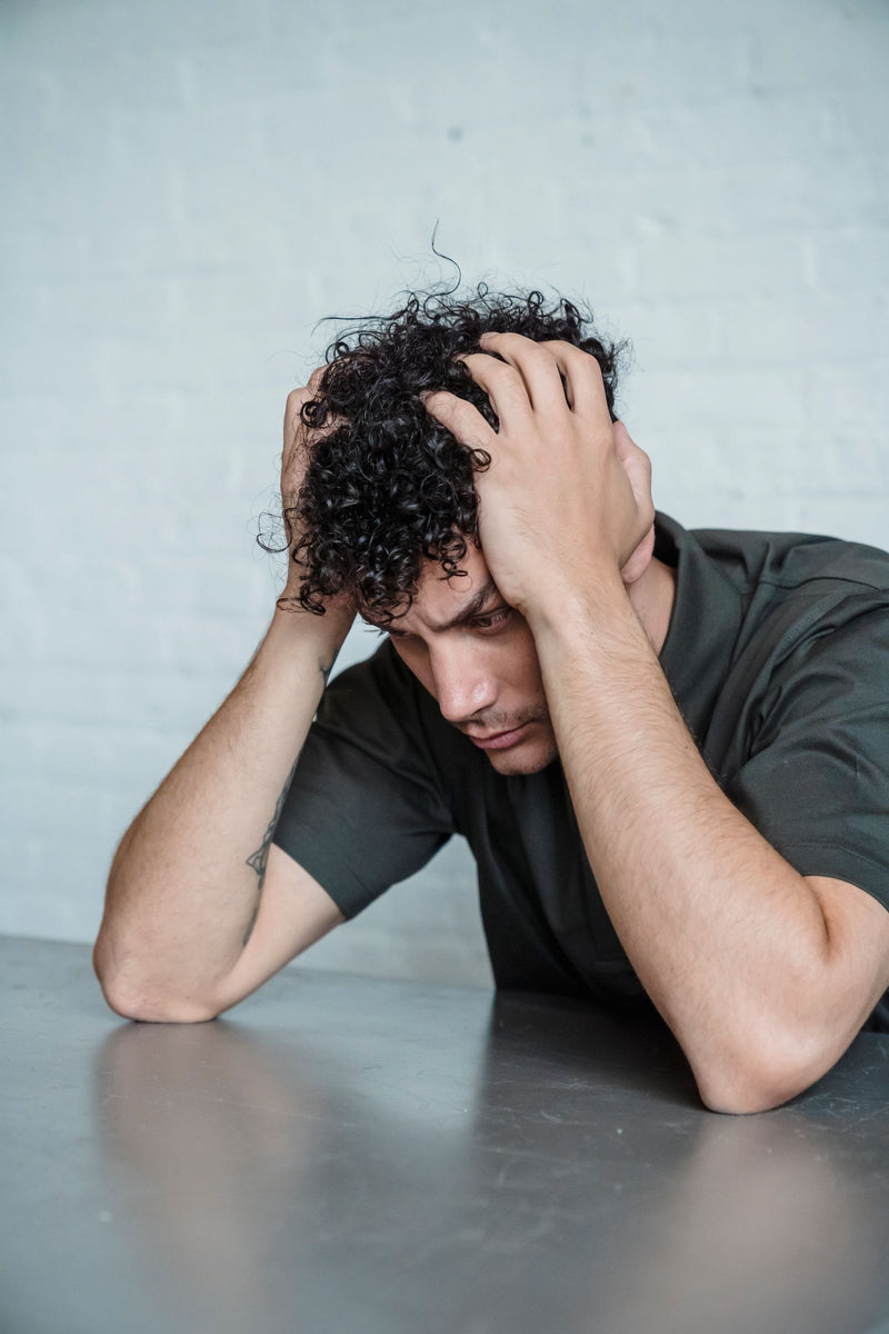 Person looking stressed and holding their head, representing everyday stress.