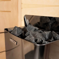 A Harvia sauna heater filled with sauna rocks, featuring illuminated control switches and a compact design.