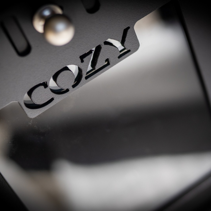 Close-up of a metallic surface with 'COZY' engraved on it.