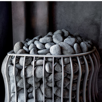 A metal basket filled with smooth gray pebbles sits against a dark, textured background. The arrangement exudes a calm, minimalist, and modern aesthetic.