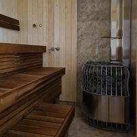 Wooden sauna interior with a bench on the left and a heater filled with dark stones on the right. The warm tones create a calm, relaxing atmosphere.